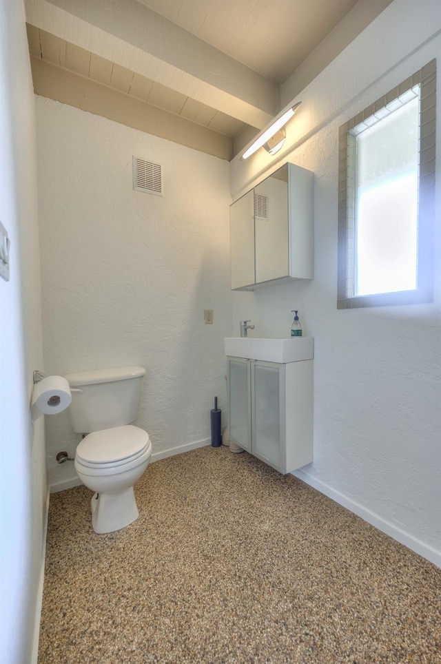 bathroom with beamed ceiling, vanity, and toilet