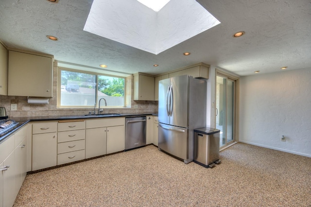 kitchen with decorative backsplash, a textured ceiling, stainless steel appliances, and sink