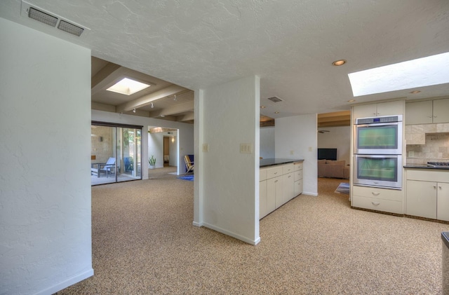 kitchen with light carpet, a textured ceiling, backsplash, and double oven