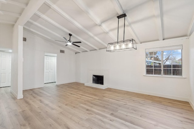 unfurnished living room with ceiling fan, light hardwood / wood-style floors, lofted ceiling with beams, and a brick fireplace