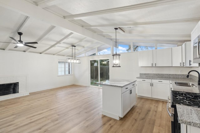 kitchen featuring sink, gas range, white cabinets, and a kitchen island