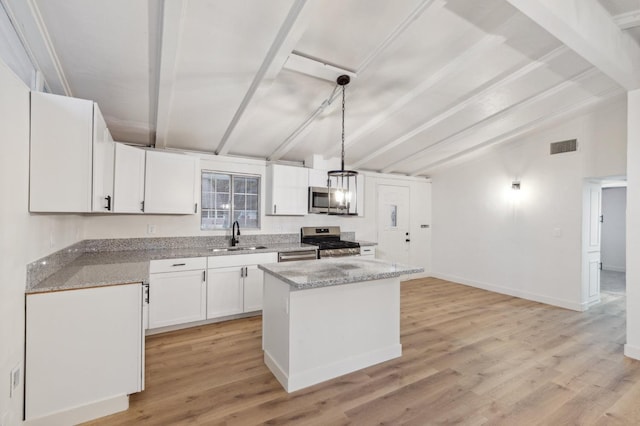 kitchen with sink, appliances with stainless steel finishes, white cabinets, a kitchen island, and decorative light fixtures