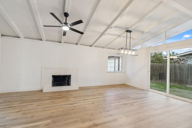 unfurnished living room featuring ceiling fan, a fireplace, lofted ceiling with beams, and light hardwood / wood-style flooring