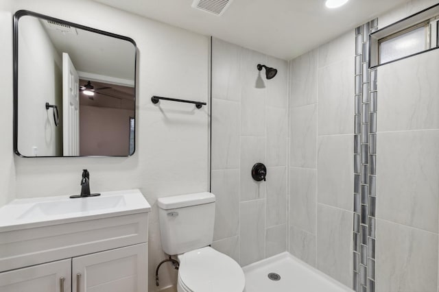 bathroom featuring vanity, a tile shower, and toilet