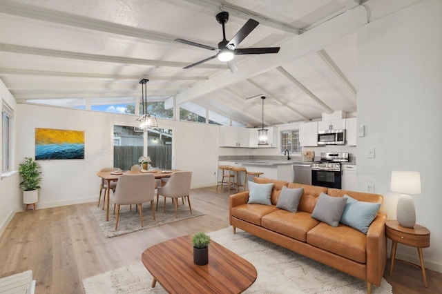 living room with lofted ceiling with beams, ceiling fan, and light wood-type flooring