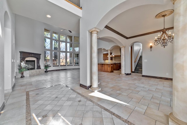 foyer with decorative columns, an inviting chandelier, a high ceiling, and ornamental molding