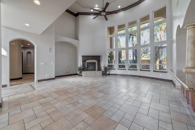 unfurnished living room featuring a towering ceiling, plenty of natural light, crown molding, and a premium fireplace