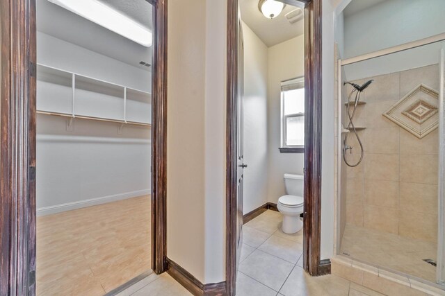 bathroom featuring tile patterned flooring, toilet, and a tile shower