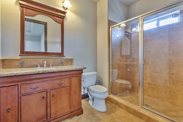 bathroom featuring tile patterned flooring, vanity, toilet, and walk in shower