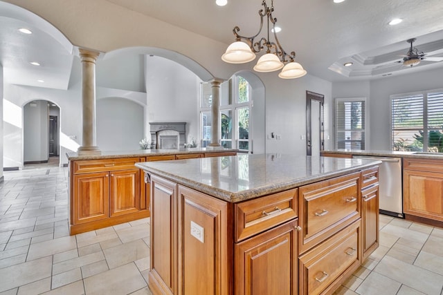 kitchen with pendant lighting, stainless steel dishwasher, a kitchen island, and ornate columns