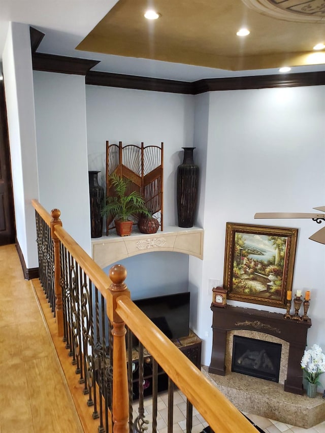 staircase with a fireplace, hardwood / wood-style floors, and ornamental molding