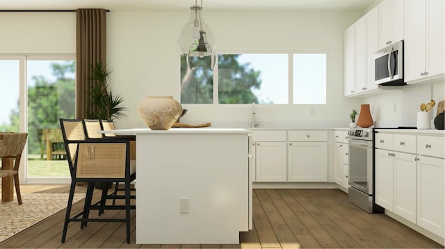 kitchen featuring white cabinets, pendant lighting, appliances with stainless steel finishes, and a breakfast bar