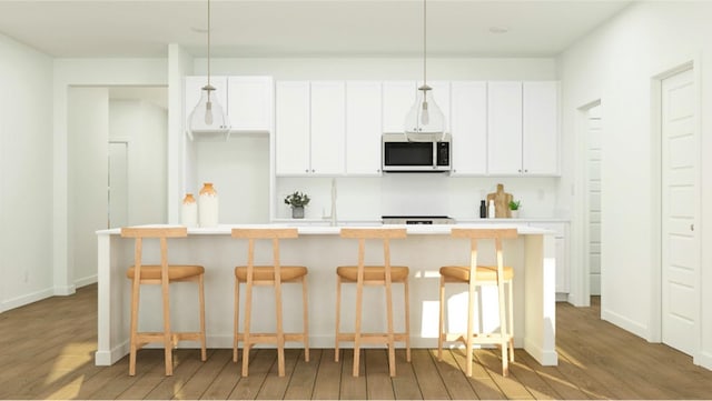 kitchen featuring a kitchen island with sink, dark wood-type flooring, white cabinetry, and a kitchen bar