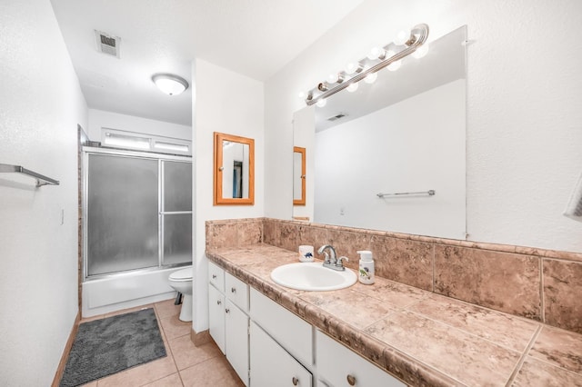 full bathroom with tile patterned flooring, vanity, toilet, and enclosed tub / shower combo