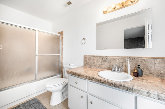 full bathroom with combined bath / shower with glass door, vanity, tile patterned floors, and toilet