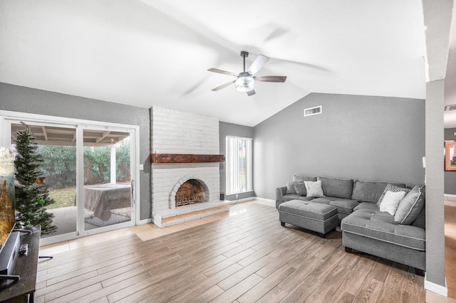 living room with light hardwood / wood-style floors, ceiling fan, a healthy amount of sunlight, and lofted ceiling