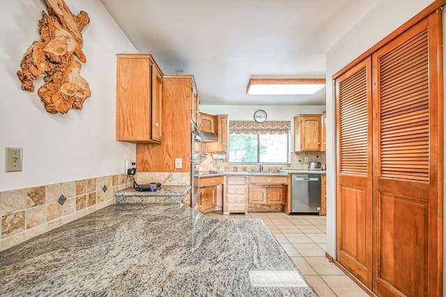 kitchen featuring sink, light stone counters, stainless steel dishwasher, decorative backsplash, and light tile patterned flooring