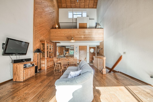 living room with wood-type flooring, a towering ceiling, and wood walls