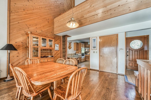 dining space featuring hardwood / wood-style floors, high vaulted ceiling, wooden ceiling, and wood walls