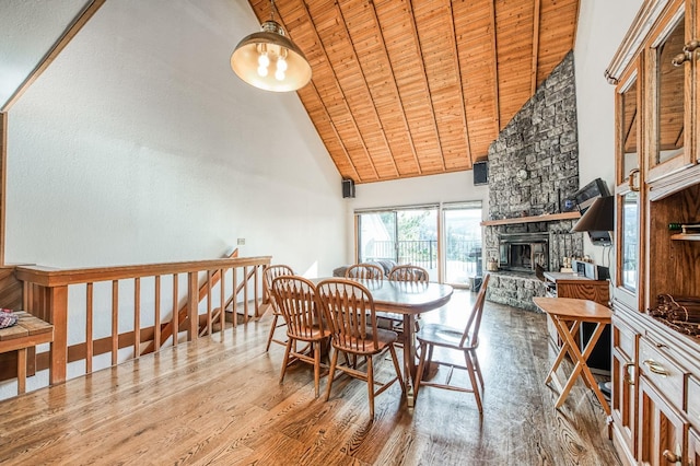 dining area with wood ceiling, a stone fireplace, high vaulted ceiling, and light hardwood / wood-style floors