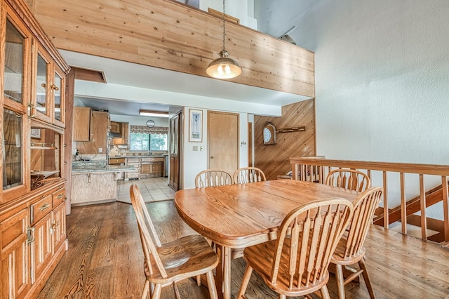 dining area with light wood-type flooring and wooden walls