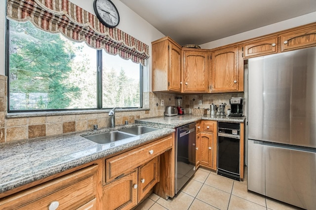 kitchen featuring sink, light stone countertops, appliances with stainless steel finishes, tasteful backsplash, and light tile patterned flooring