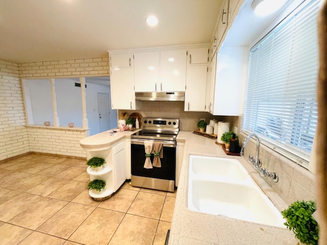 kitchen with sink, white cabinetry, electric range, brick wall, and light tile patterned flooring