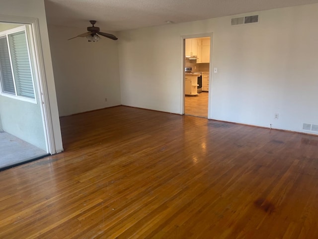 unfurnished room featuring dark hardwood / wood-style floors, ceiling fan, and a textured ceiling