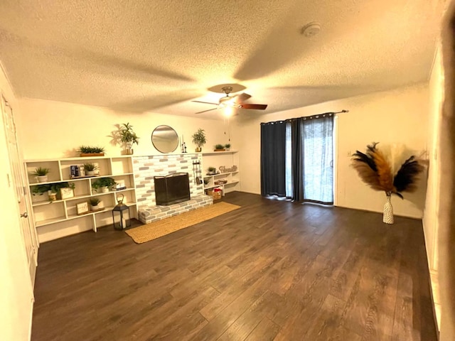 living room featuring ceiling fan, dark hardwood / wood-style flooring, a brick fireplace, and a textured ceiling