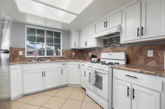 kitchen with white cabinetry, sink, white range with gas stovetop, decorative backsplash, and light tile patterned floors