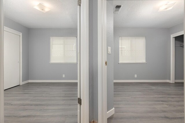 corridor with light hardwood / wood-style floors and a textured ceiling