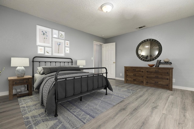 bedroom with wood-type flooring and a textured ceiling