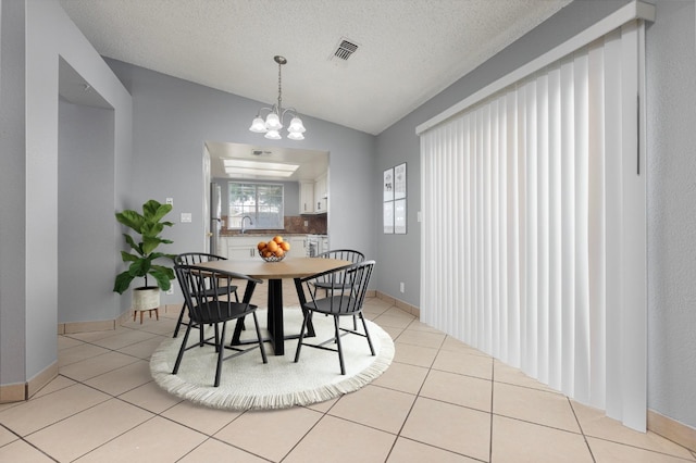 dining room featuring a textured ceiling, sink, light tile patterned floors, and vaulted ceiling