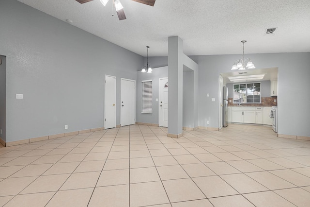 unfurnished living room with sink, a textured ceiling, lofted ceiling, light tile patterned floors, and ceiling fan with notable chandelier