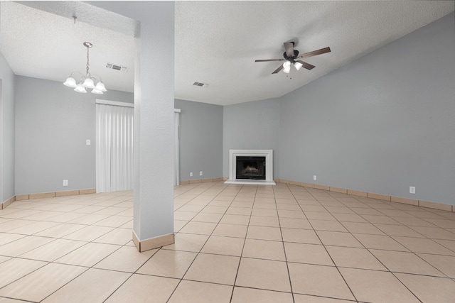 unfurnished living room with ceiling fan with notable chandelier, a textured ceiling, and light tile patterned flooring