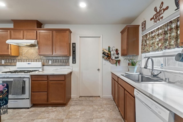 kitchen featuring backsplash, range with gas cooktop, white dishwasher, and sink