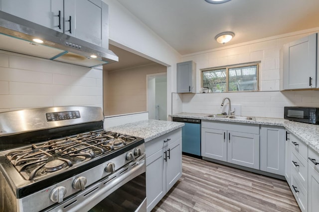 kitchen featuring light stone countertops, sink, stainless steel appliances, light hardwood / wood-style flooring, and backsplash