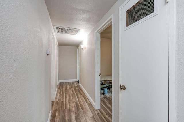 hallway featuring a textured ceiling and light hardwood / wood-style flooring