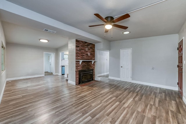 unfurnished living room with ceiling fan, wood-type flooring, and a brick fireplace