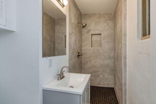 bathroom with vanity, a textured ceiling, and tiled shower