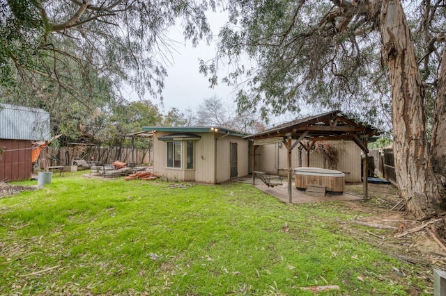 back of property with a patio area, a yard, and a hot tub