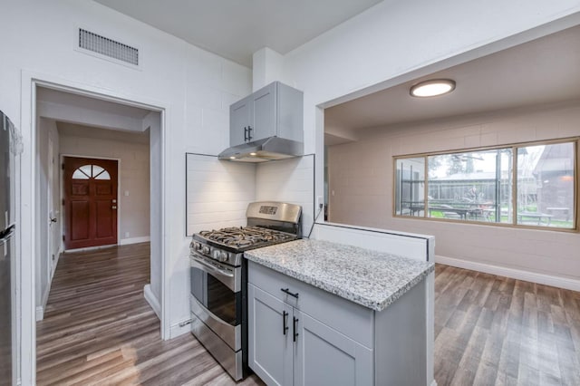 kitchen featuring gas range, dark hardwood / wood-style floors, light stone counters, and gray cabinetry