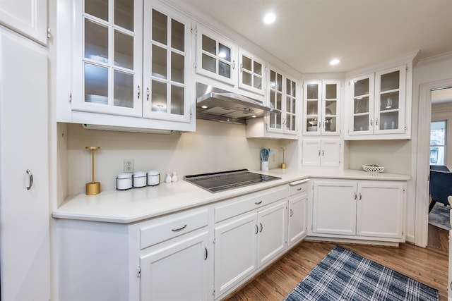 kitchen with black stovetop, white cabinets, dark wood-type flooring, and ornamental molding