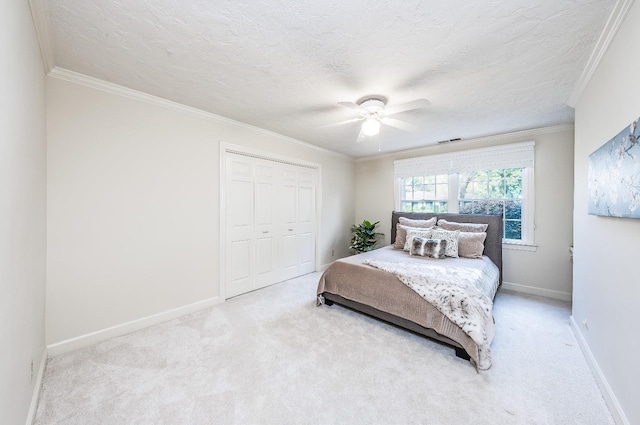 carpeted bedroom with a textured ceiling, a closet, ceiling fan, and ornamental molding