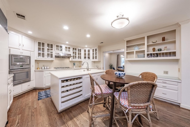 kitchen with stainless steel oven, kitchen peninsula, stovetop, dark hardwood / wood-style flooring, and white cabinetry