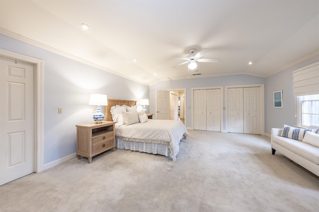 carpeted bedroom with ceiling fan, two closets, crown molding, and vaulted ceiling