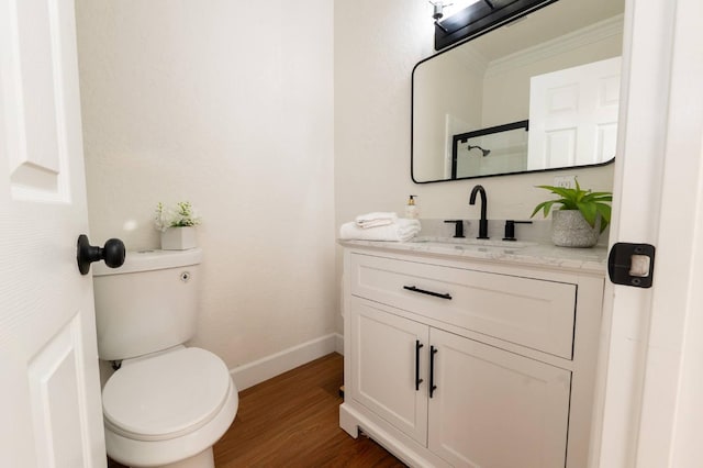 bathroom featuring ornamental molding, toilet, vanity, and wood-type flooring