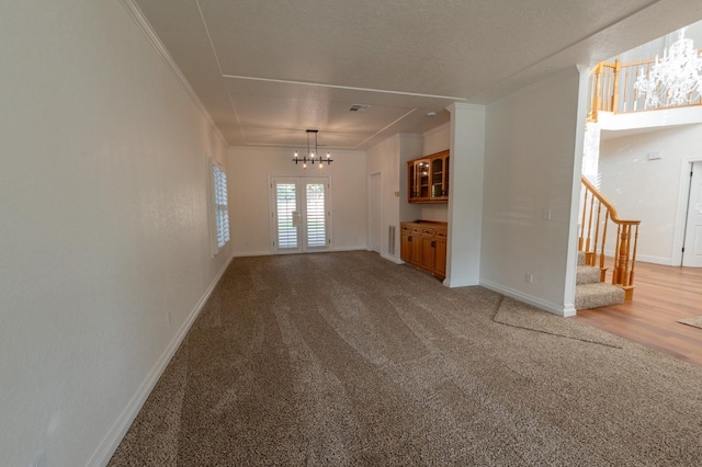 unfurnished living room with an inviting chandelier, carpet floors, and ornamental molding