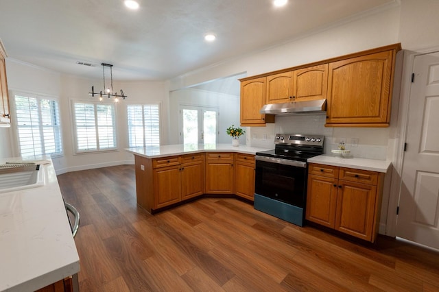 kitchen featuring stainless steel electric range, kitchen peninsula, decorative light fixtures, ornamental molding, and dark hardwood / wood-style floors