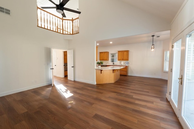 unfurnished living room featuring ceiling fan, dark wood-type flooring, and high vaulted ceiling